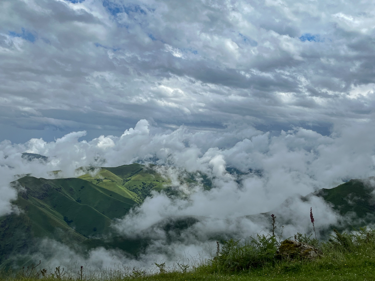 Clouds breaking over green mountain ridges near the summit